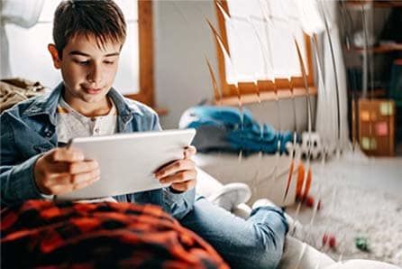 Image of a young mnale online student on his tablet working on a Pearson Online Academy virtual class. 